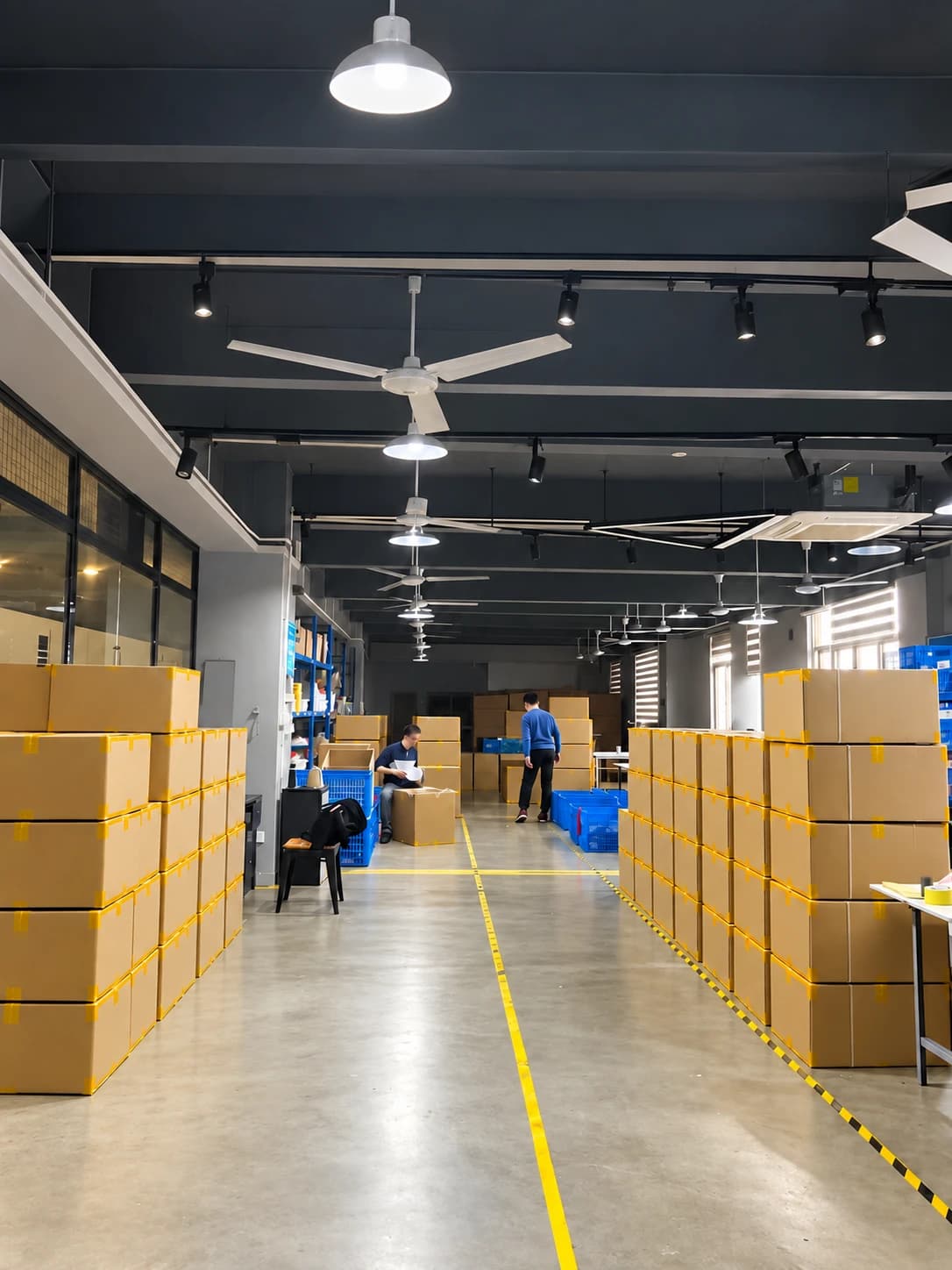 Finished-goods warehouse with stacked cartons on either side of a marked aisle
