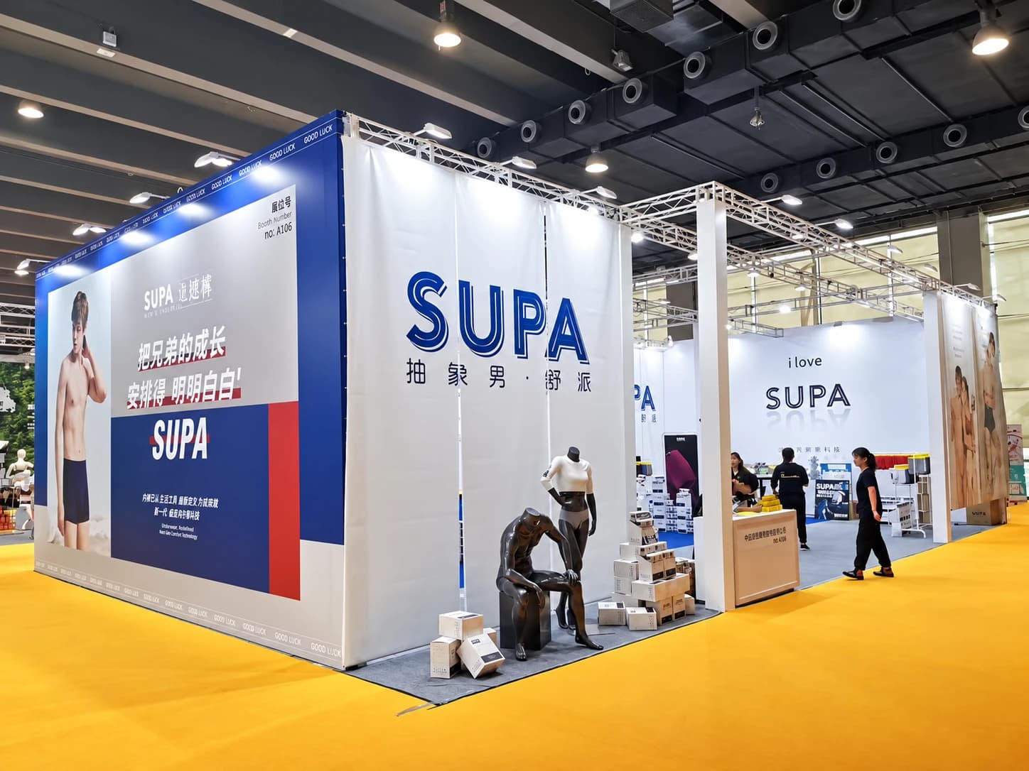 Exhibition booth with SUPA and Abstract Man signage, underwear displays, and packaged products