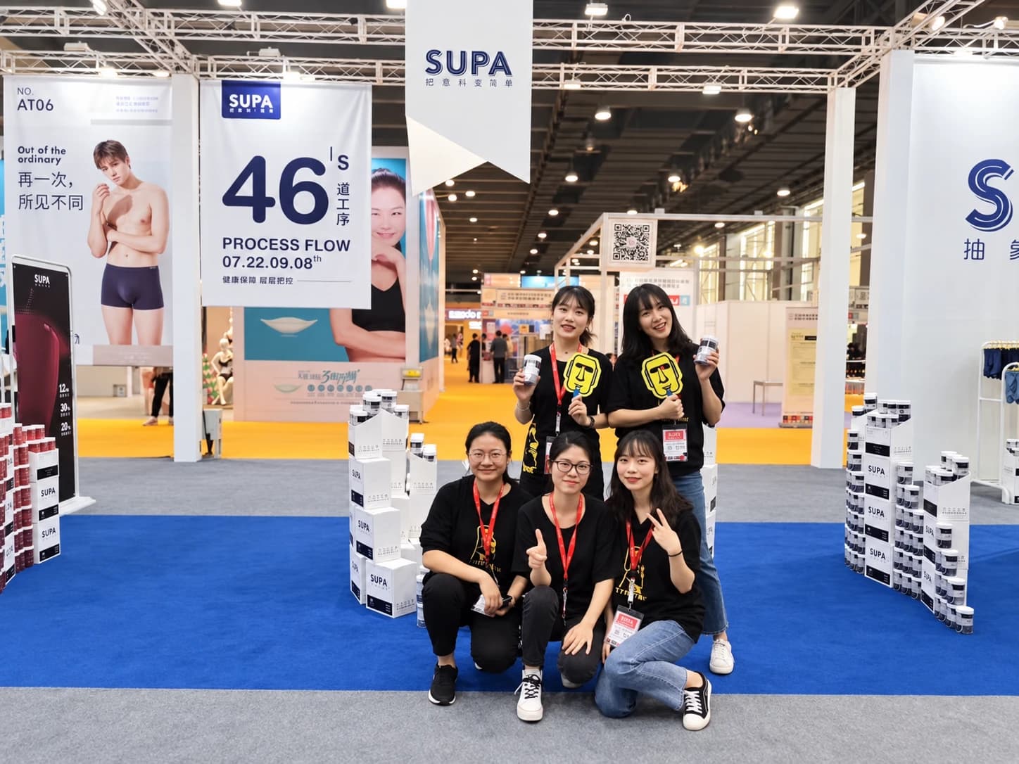 Five team members posing with packaged products at the exhibition booth